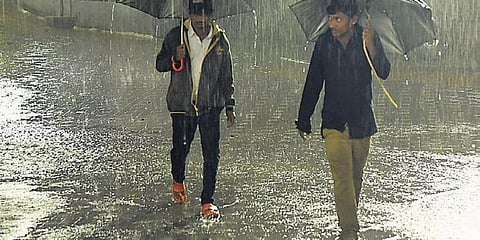 ಮಳೆಯಲ್ಲಿ ನಗರದ ರಸ್ತೆಯಲ್ಲಿ ನಡೆದು ಹೋಗುತ್ತಿರುವ ಇಬ್ಬರು ವ್ಯಕ್ತಿಗಳು.