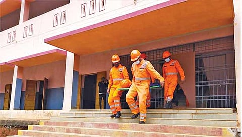 கட்டிடத்தில் சிக்கிய ஒருவரை மீட்டுவரும் பேரிடர் குழுவினர்.