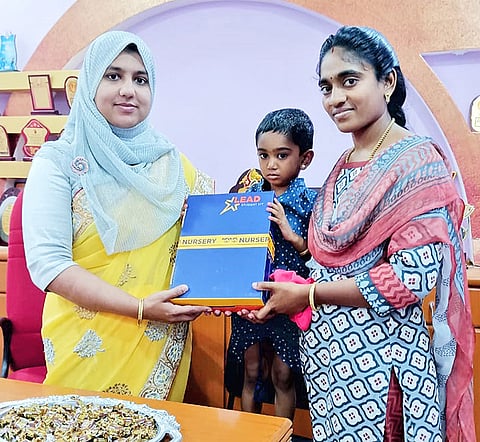 பள்ளியின் முதல்வர் சமீமா பர்வீன் குழந்தைக்கு  பாடப் புத்தகம் வழங்கினார்.