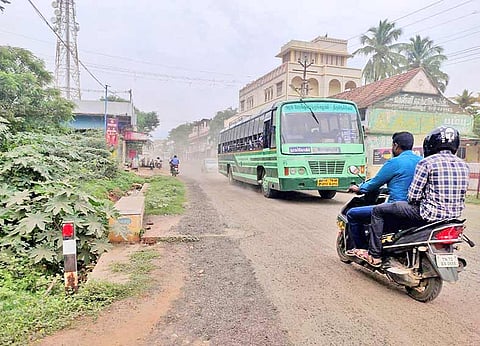 பேருந்தின் பின்பு சாலையில் தூசி பறக்கும் காட்சி.