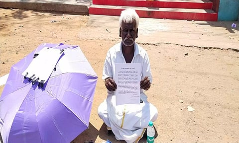 கலெக்டர் அலுவலகம் அருகே உள்ள ஆஞ்சநேயர் கோவில் தரையில் அமர்ந்து  நாராயணன் போராட்டம் செய்த காட்சி.