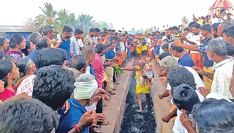 குழந்தையுடன் பக்தர் ஒருவர் தீ குண்டத்தில் இறங்கி நேர்த்திக்கடன் செலுத்திய காட்சி.&nbsp;