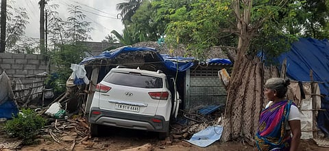 கார் கூரை வீட்டிற்குள் புகுந்து நிற்கும் காட்சி.