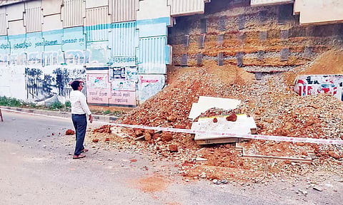 உயர்மட்ட பாலத்தின் பக்கவாட்டு சுவர் சரிந்து விழுந்து கிடப்பதை படத்தில் காணலாம்.&nbsp;