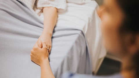 Representative image - A nurse holding her patients hand.
