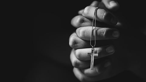 Symbolic image of hands holding cross while praying.