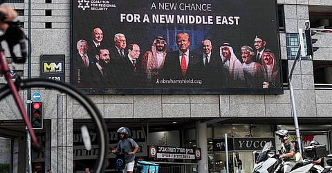 People walk by a billboard sponsored by the Coalition for Regional Security calling for the expansion of the Abraham Accords, in Ramat Gan, Israel 