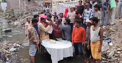 
BJP councillor protests by cutting birthday cake while standing in a drain