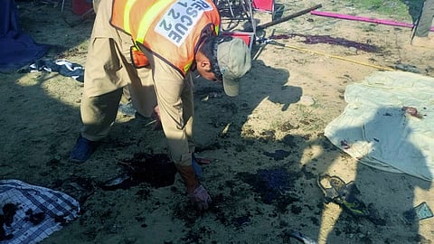 In this photo provided by Rescue 1122 Head Quarters, rescue workers inspect the site after a bomb explosion in the Bajur district of Khyber Pakhtunkhwa, Pakistan, Sunday, July 30, 2023. 
