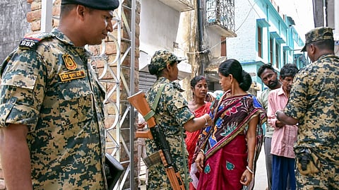 Voters wait for security check-up at a polling station during the first phase of the West Bengal Assembly election, in Nandigram, Purba Medinipur district, Thursday, April 23, 2026.