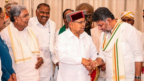 Karnataka Governor Thaawarchand Gehlot congratulates Congress President D K Shivakumar after receiving a letter from the latter, who staked claim to form a new government following his election as leader of the legislature party, in Bengaluru on May 30, 2026. Party leader and former state CM Siddaramaiah is also seen.