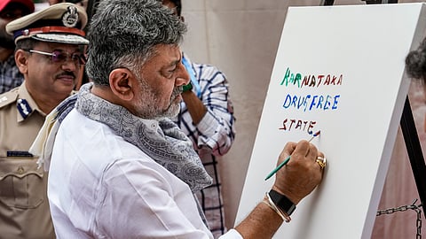 Karnataka Chief Minister DK Shivakumar writes on a canvas during an event to celebrate International Day against Drug Abuse and Illicit Trafficking, in Bengaluru, Tuesday, June 30, 2026. 