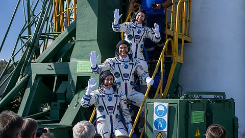 Expedition 75 Roscosmos cosmonaut Anna Kikina, top, NASA astronaut Anil Menon, middle, and Roscosmos cosmonaut Pyotr Dubrov, bottom, wave farewell prior to boarding the Soyuz MS-29 spacecraft for launch, Tuesday, July 14, 2026 at the Baikonur Cosmodrome in Kazakhstan.
