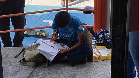 En las imágenes se puede apreciar al niño sentado junto a una mochila y un cartel en el que pide que las personas lo apoyen (Foto: cortesía)