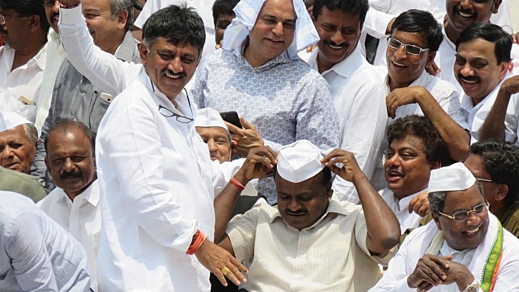 Janata Dal (Secular) chief minister of Karnataka HD Kumaraswamy (centre) delights senior Karnataka Congress leader DK Shivakumar (standing) and former Karnataka CM Siddaramaiah (right)  as he tries on a Congress cap&nbsp;