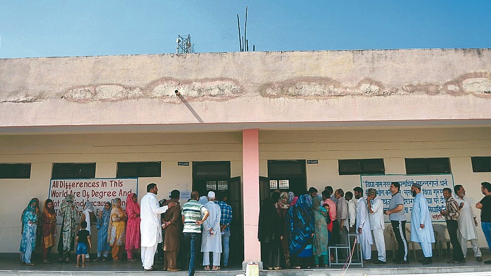 People wait in  queues to cast their votes at a polling station during municipal elections in Jammu