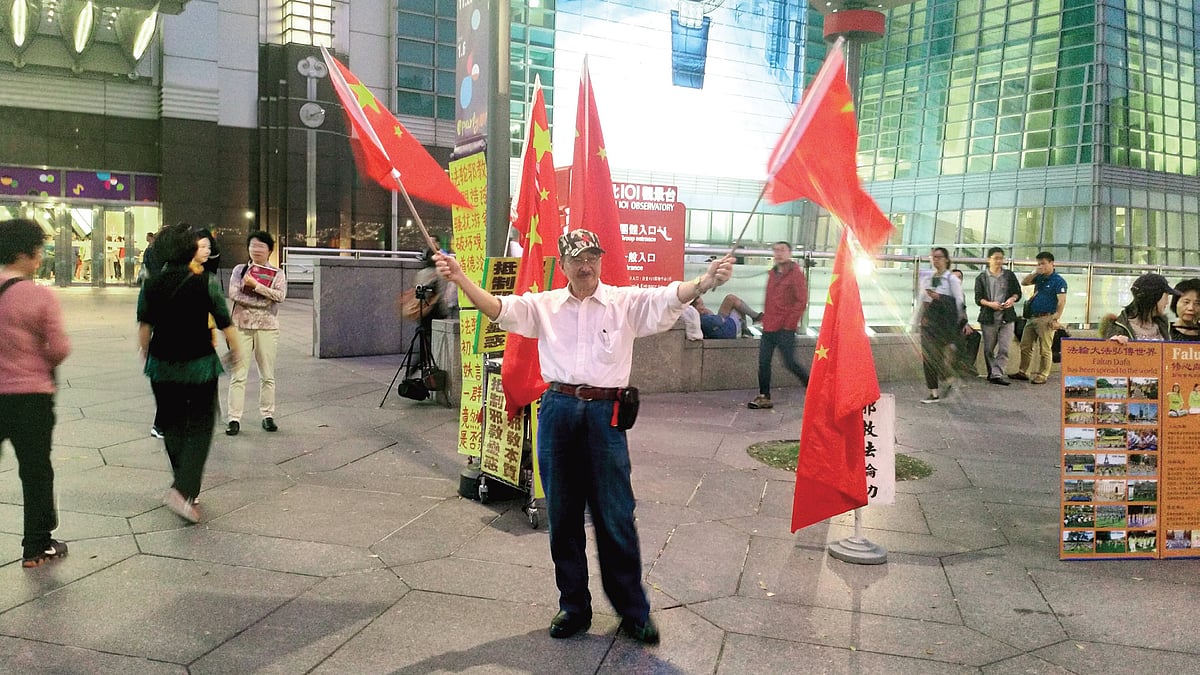 A protestor demanding reunification with China waves Chinese flags at Taipei 101