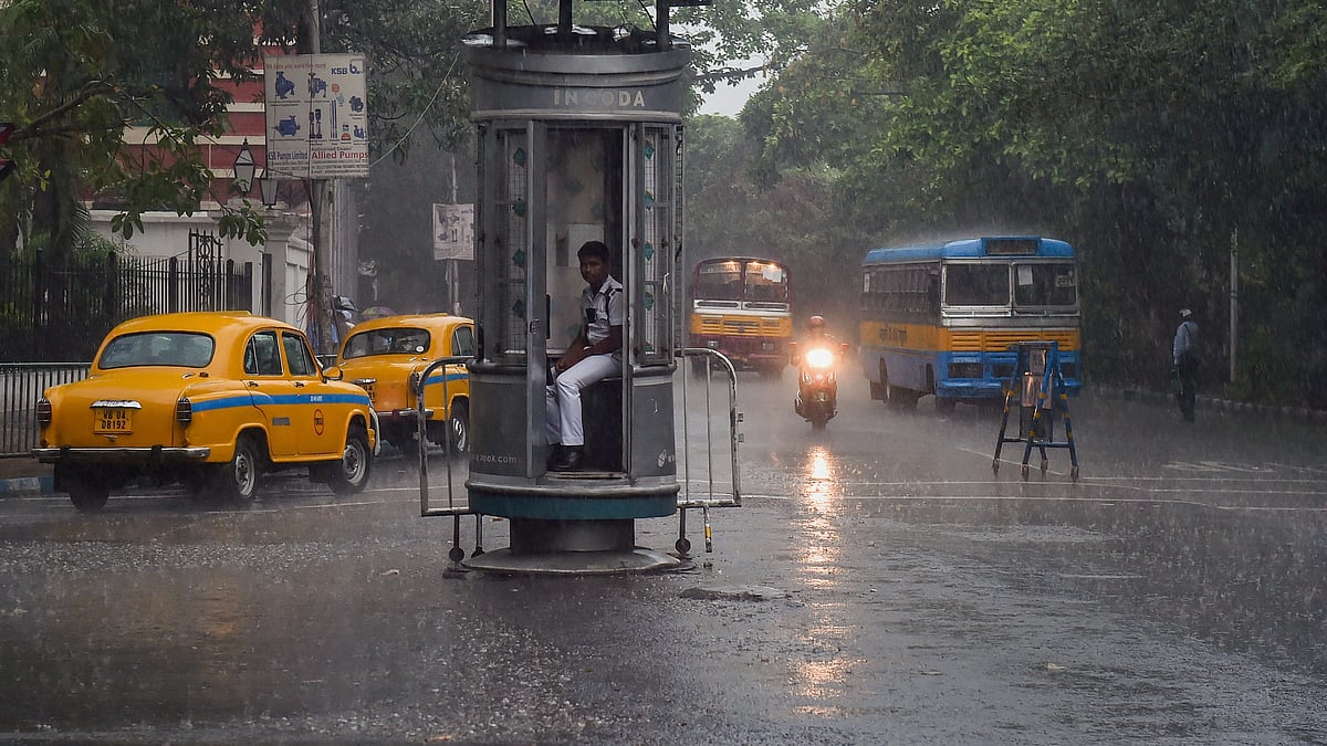 A traffic police personnel sits inside a kiosk during rainfall, in Kolkata, Friday, May 3