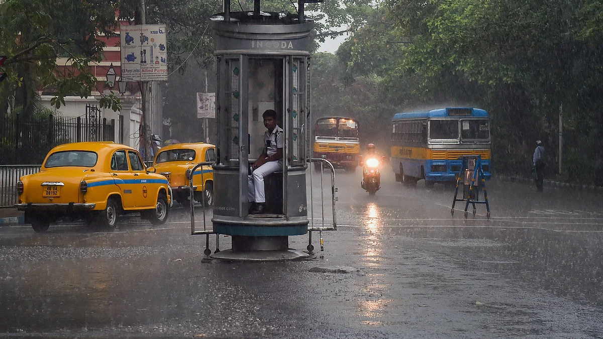 A traffic police personnel sits inside a kiosk during rainfall, in Kolkata, Friday, May 3