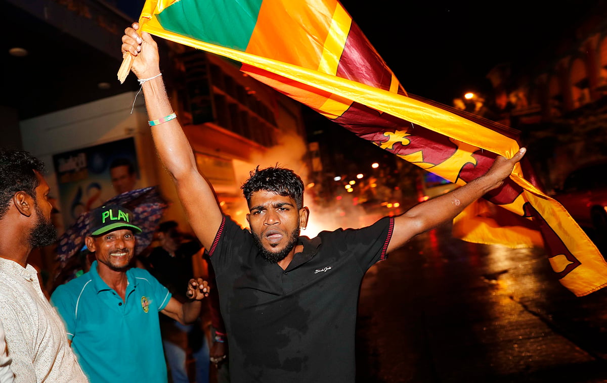 A supporter of Sri Lanka’s governing party waves  national flag as they mark the close of presidential election in Colombo on Saturday. The polls were marred by shots fired at a onvoy of Muslims heading to cast their votes. (Photo: AP/PTI)