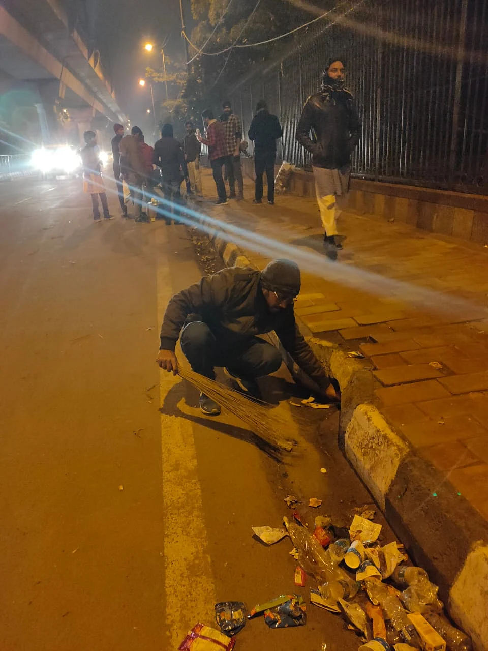 A  student picking up trash at the protest site outside Jamia Millia to dump it in the dustbin. (Photo courtesy: Social media)