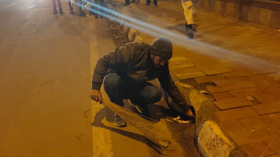 A  student picking up trash at the protest site outside Jamia Millia to dump it in the dustbin. (Photo courtesy: Social media)