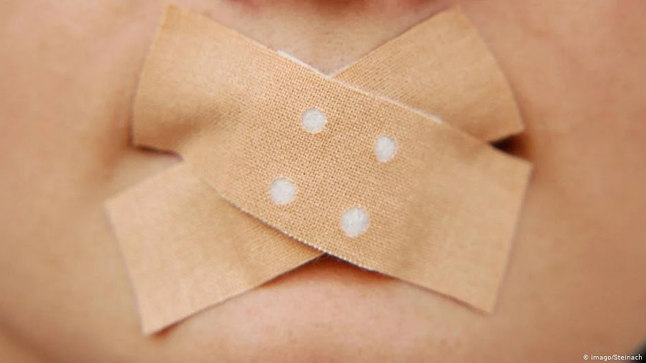 Throttling freedom of expression puts democracy at risk and infantilises citizens—and in this case, risks double jeopardy, says the Constitutional Conduct Group. (Representative image shows bandages stuck over a person's mouth.)