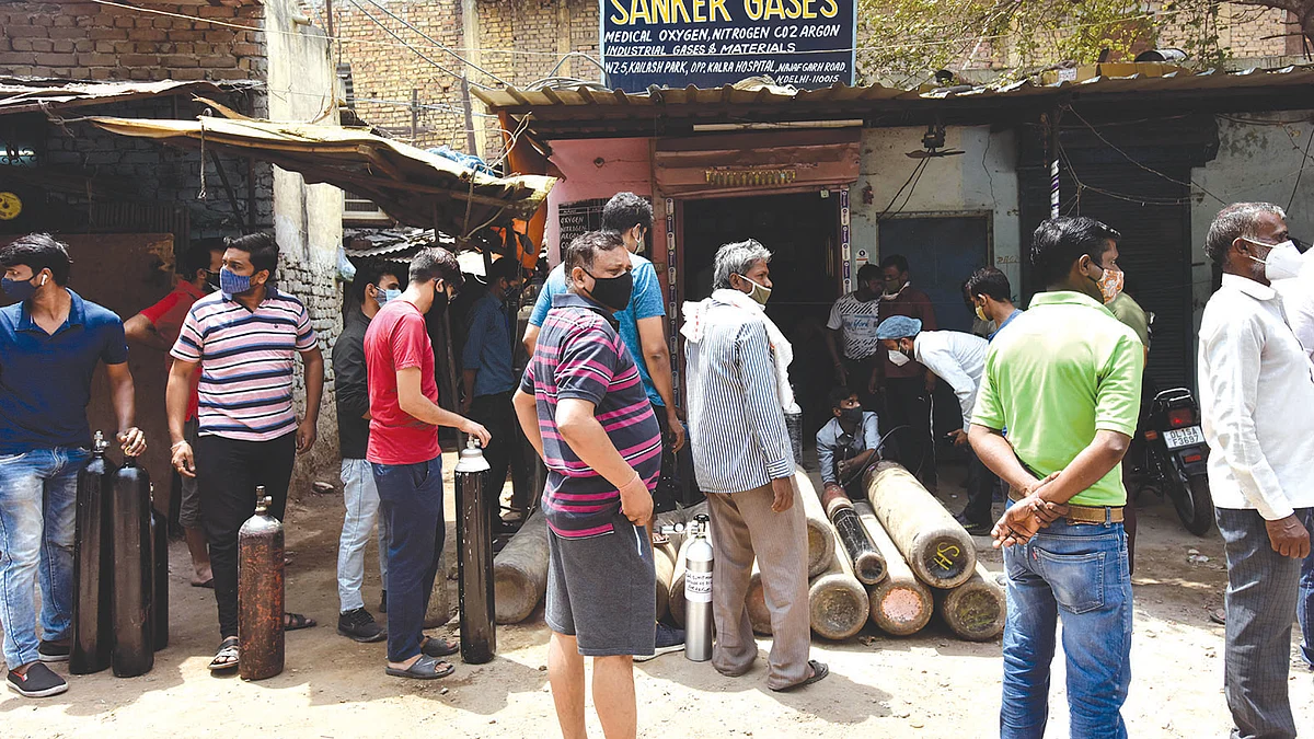 People queue up to get their oxygen cylinders refilled at a retailer