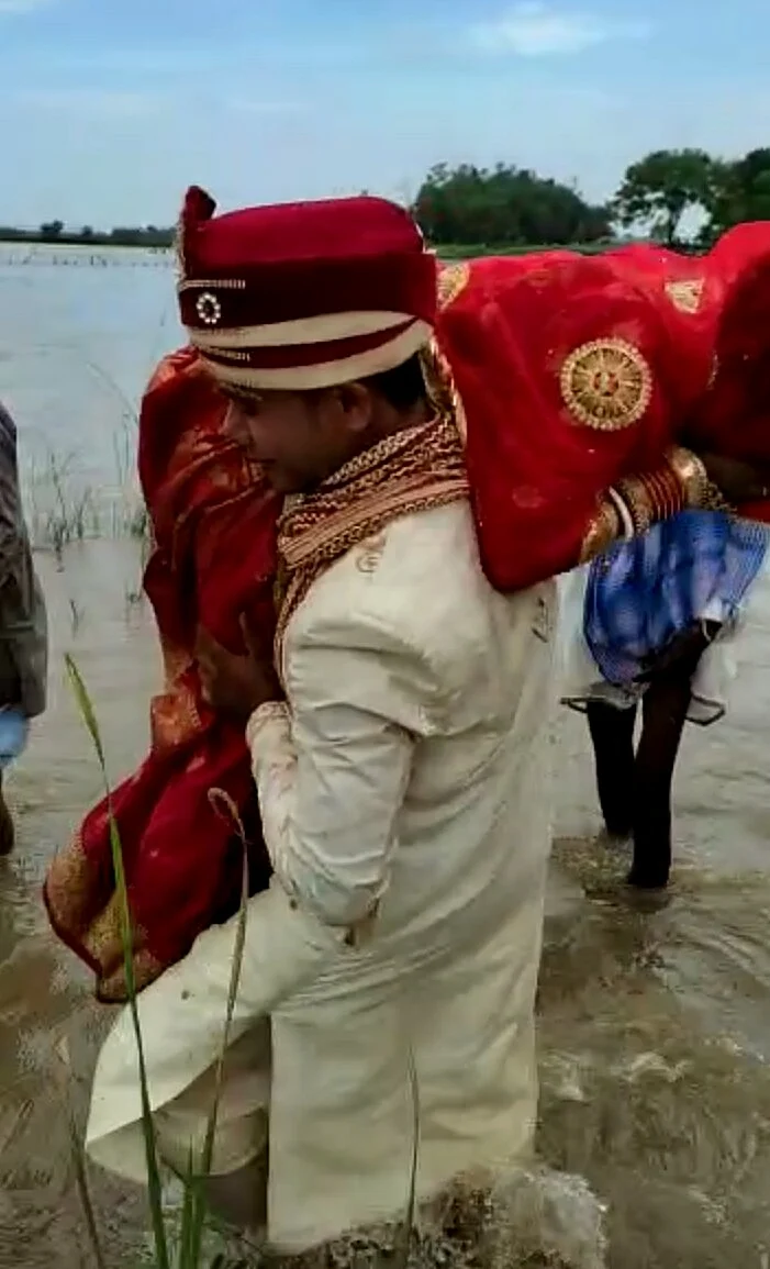The groom can be seen lifting his newly wed bride on his shoulder to carry her across the river.