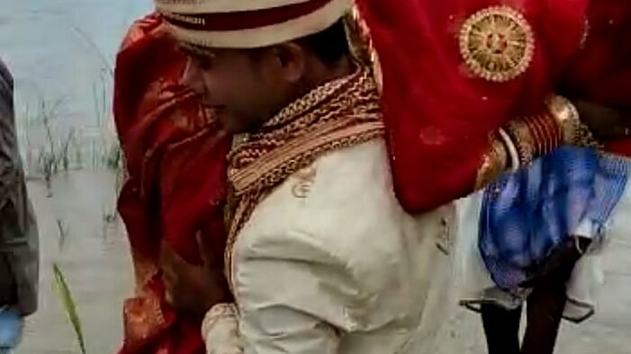 The groom can be seen lifting his newly wed bride on his shoulder to carry her across the river.