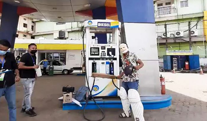 A man wearing PM Modi's mask gives a celebratory pose of a batsman as petrol & diesel prices breach Rs 100/l mark