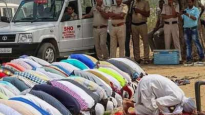 Police stand guard as Muslim offer Friday prayers in an open space in Gurgaon
