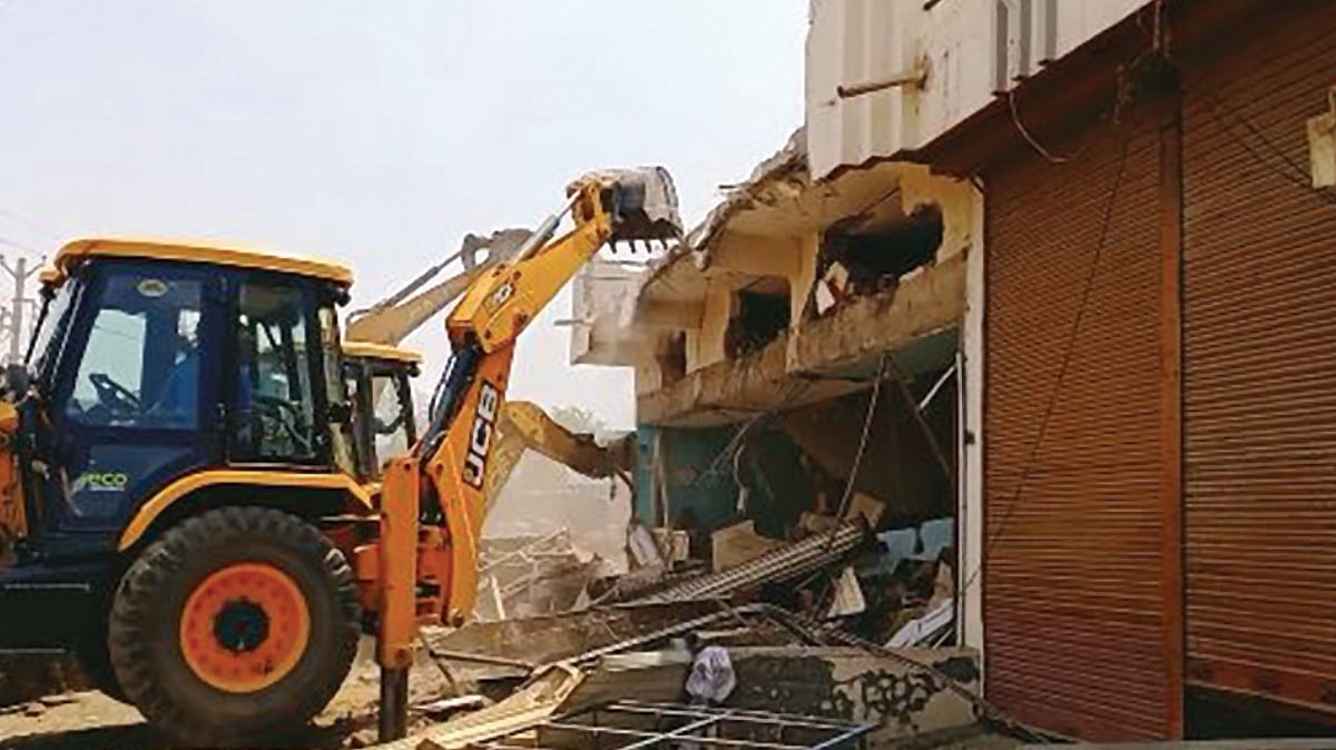 A bulldozer demolishing houses and shops in Khargone, Madhya Pradesh