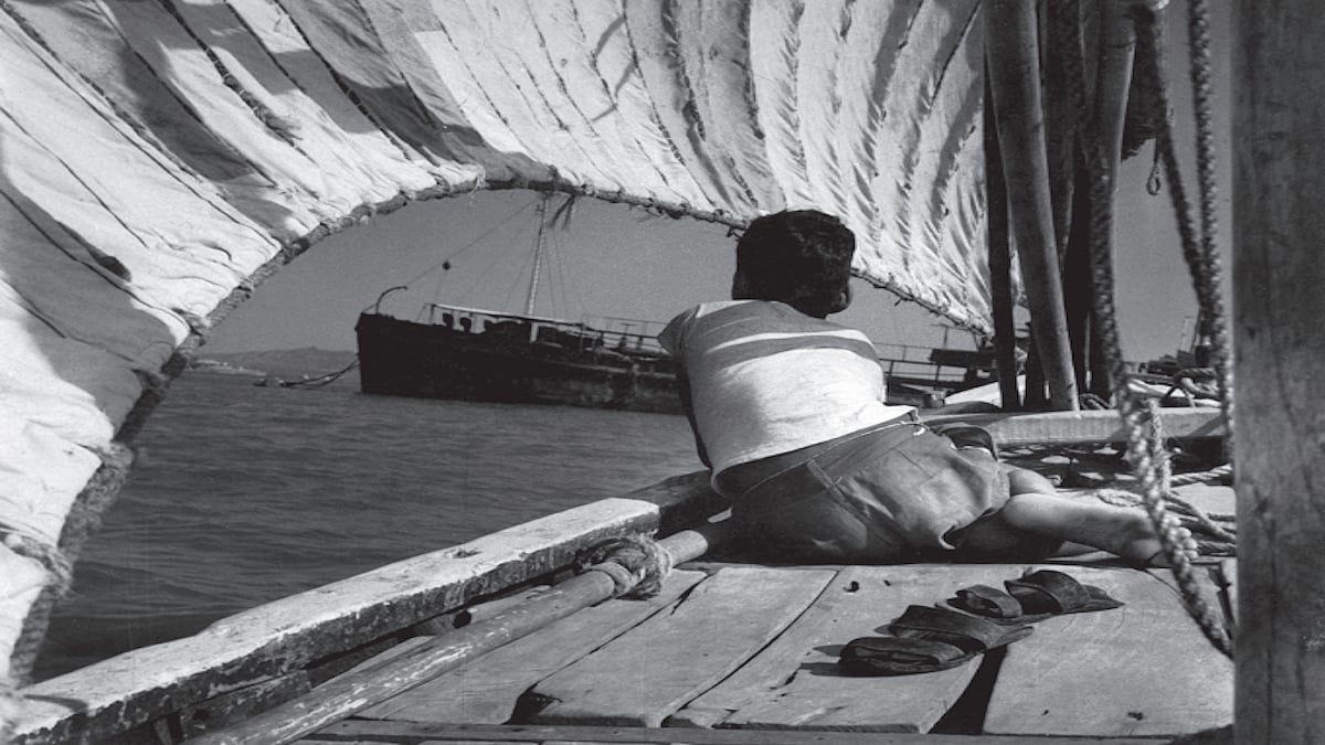 A boy sitting in a country boat looking at a ship, 1940s by Manobina Roy