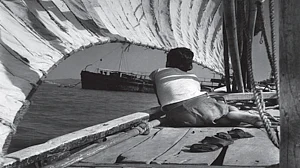 A boy sitting in a country boat looking at a ship, 1940s by Manobina Roy