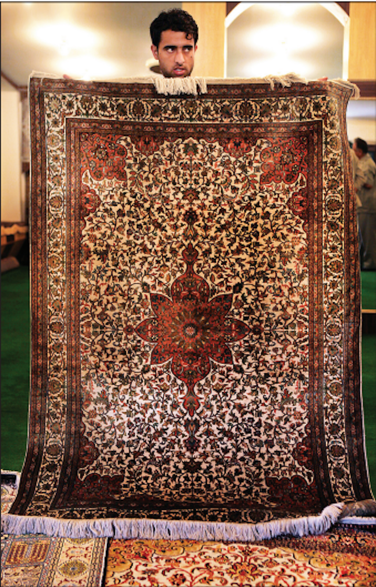 A salesman shows a hand-woven silk Kashmiri carpet at a shop in Srinagar (Photo: getty images)