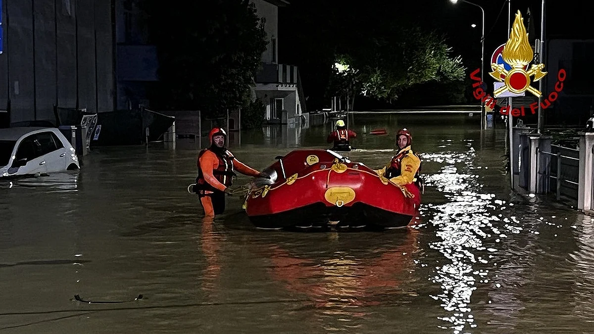 Rescuers push a boat on a flooded street in Marche, Italy, on September 16, 2022. (Italian Firefighters/Handout via Xinhua/IANS)