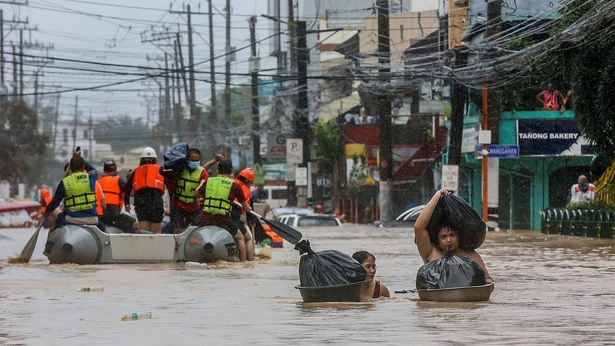Residents carry their belongings through the flood. (Photo: IANS)