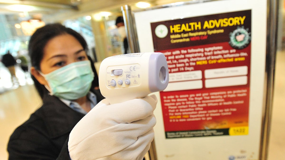 An officer holding a digital thermometer checks people's body temperature at Suvarnabhumi Airport in Bangkok, Thailand. (Photo: Xinhua/Rachen Sageamsak/IANS)