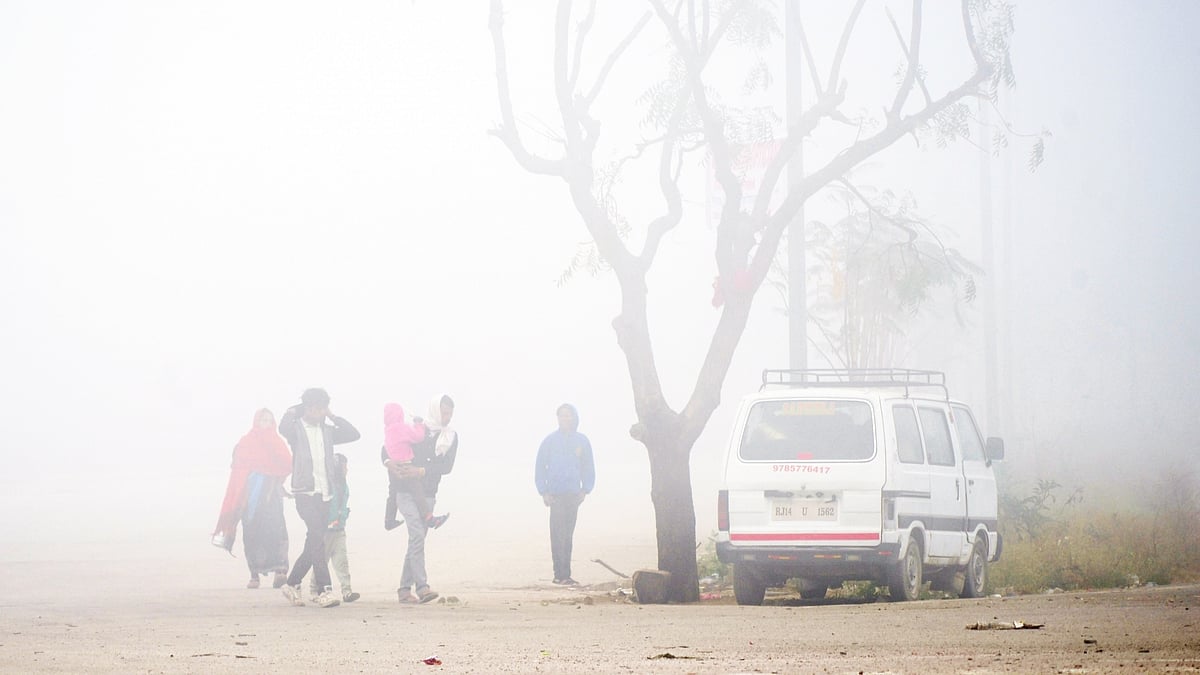People walk past amid dense fog covering the area on a cold winter day, in Jaipur. (Photo: IANS/Ravishankar Vyas)