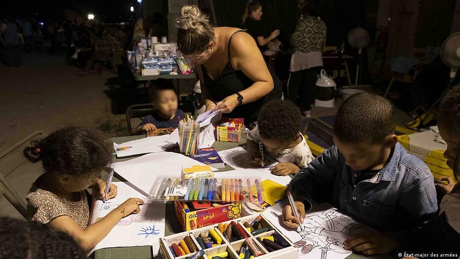 Children drawing on sheets of paper surrounded by art supplies