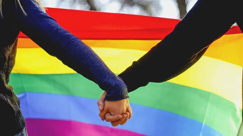 Representative image of a couple holding hands in front of a Pride flag (Photo: Getty Images)