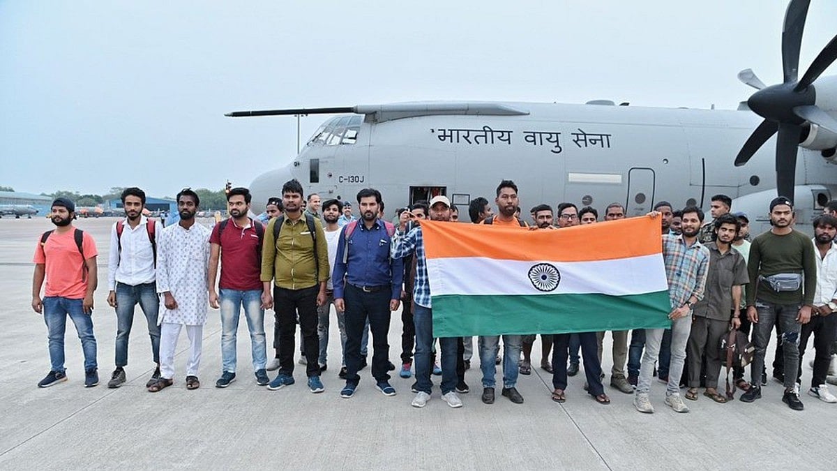 People rescued from Sudan standing in front of an Indian aircraft holding the Indian flag (Photo Courtesy: @DrSJaishankar)