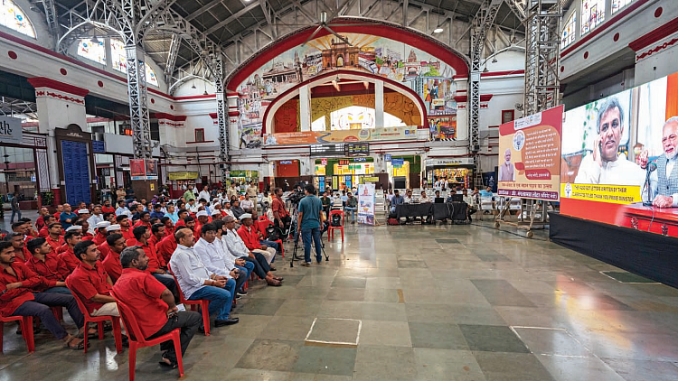 Porters listen to the 100th episode of PM Modi’s monthly radio broadcast ‘Mann Ki Baat’ at Mumbai Central railway station (Photo: Getty Images)