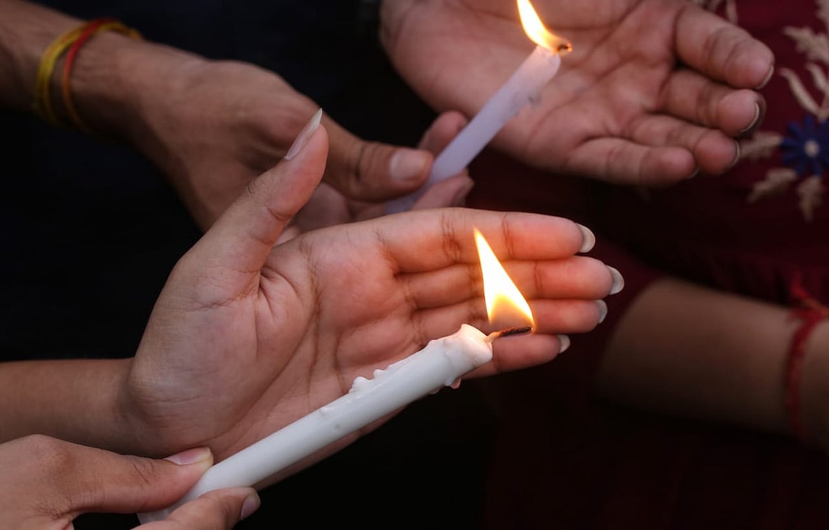 Photo shows hands holding lit candles (NH Photos by Vipin)