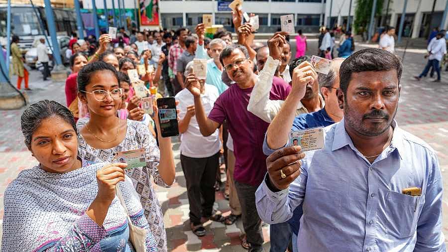 People wait in queues at a polling station to cast their votes for Karnataka Assembly elections, in Bengaluru. (Photo Courtesy: PTI)
