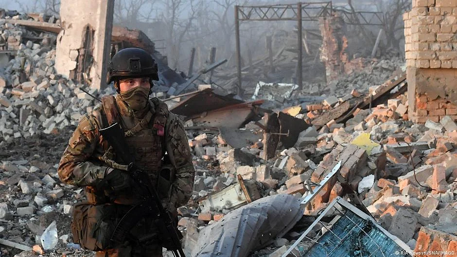 A Russian soldier standing amidst rubble (DW)