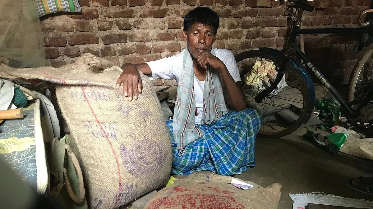 Pahar Toli’s Gram Pradhan, Ban Singh Munda, sits beside sacks of fortified rice supplied to the village (photo courtesy Shreegireesh Jalihal/ The Reporters' Collective)