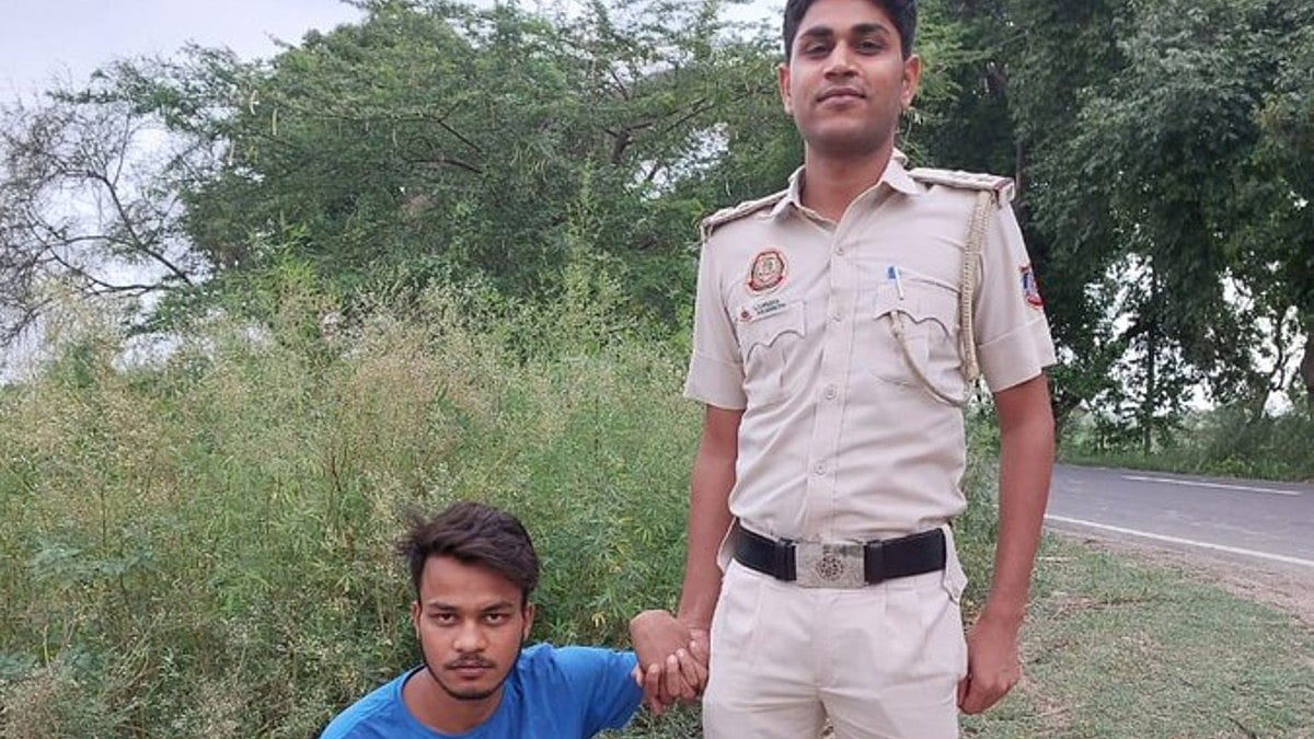 The accused with a police officer (photo courtesy @upuknews1/Twitter)
