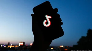 The silhouette of a hand holding up a phone which has the TikTok logo on the screen (DW)